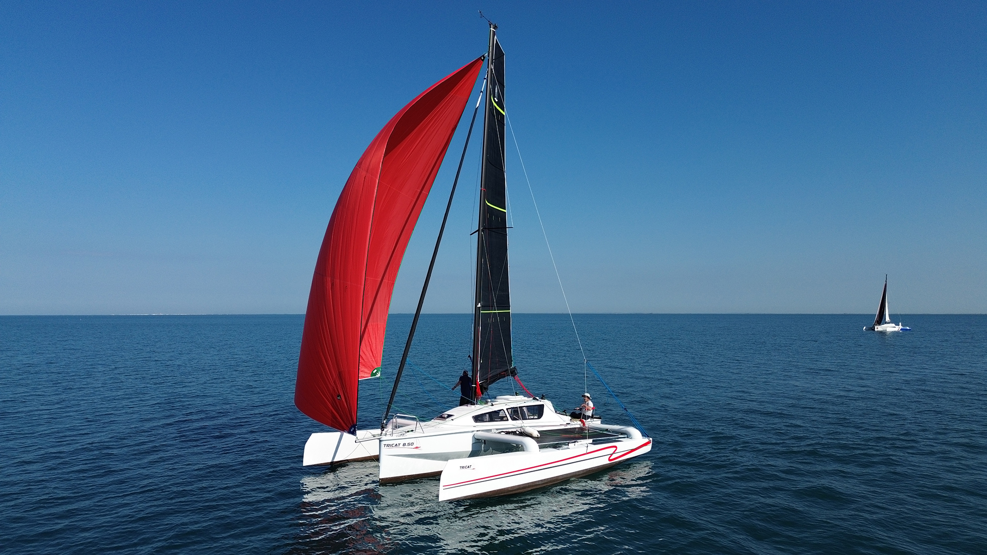 Tricat 8.50 with black mainsail cruising on smooth water